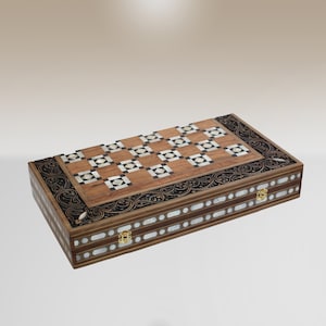 Puede incluir: Un tablero de backgammon de madera con intrincados detalles de nácar y latón incrustados. El tablero está cerrado y presenta un diseño tradicional.