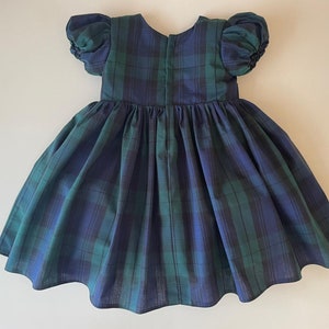 Peut inclure: Une robe &agrave; carreaux bleus et verts avec des manches bouffantes. La robe a une jupe pliss&eacute;e et une fermeture &eacute;clair dans le dos.