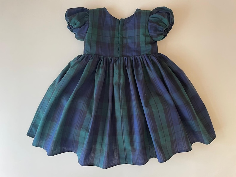 Peut inclure: Une robe &agrave; carreaux bleus et verts avec des manches bouffantes. La robe a une jupe pliss&eacute;e et une fermeture &eacute;clair dans le dos.