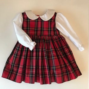 May include: A red and black plaid dress with a white Peter Pan collar and long sleeves. The dress has a gathered skirt and is made of a soft, comfortable fabric.