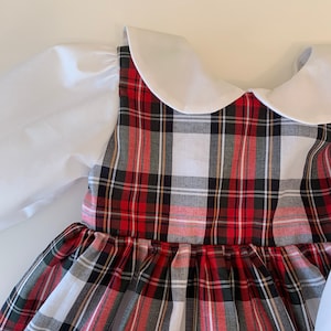 May include: A red and white plaid dress with a white Peter Pan collar and puffed sleeves. The dress has a gathered skirt and is made of a soft, comfortable fabric.