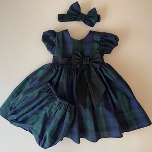 Peut inclure: Une robe &agrave; carreaux avec un n&oelig;ud noir et un bandeau assorti. La robe a des manches bouffantes et une jupe ample.
