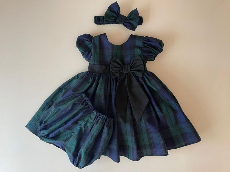 Peut inclure: Une robe &agrave; carreaux avec un n&oelig;ud noir et un bandeau assorti. La robe a des manches bouffantes et une jupe ample.
