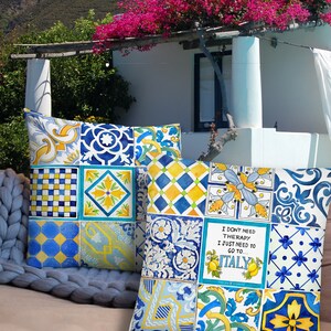 May include: Two decorative throw pillows with a patchwork design of blue, yellow, and white tiles. The pillows feature a quote that reads "I don't need therapy I just need to go to Italy".