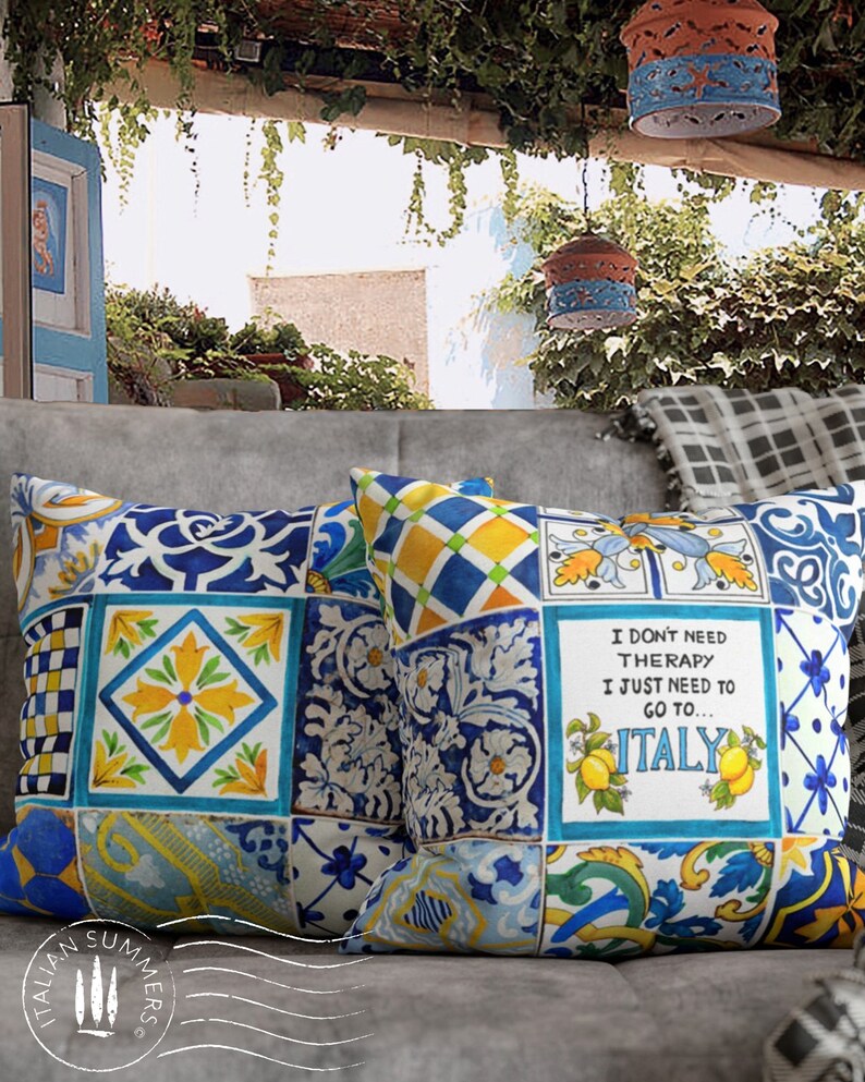 May include: Two decorative throw pillows with a blue and yellow Italian tile pattern. One pillow features the text "I don't need therapy I just need to go to... ITALY".