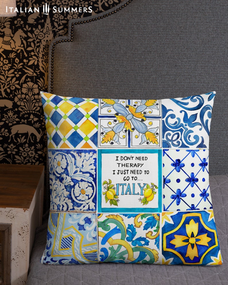 May include: A decorative pillow with a patchwork design featuring blue, yellow, and white tiles. The pillow has a quote that reads "I don't need therapy I just need to go to... ITALY".