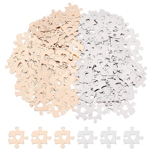 May include: A large quantity of gold and silver metal puzzle pieces with a heart-shaped cutout in the center. The pieces are scattered on a white background.