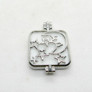 May include: Silver charm with a crescent moon and stars design. The charm is square shaped and has a hinged opening.
