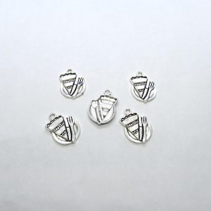 May include: Five silver charms shaped like a plate with a slice of pie and a fork on it.