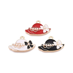 May include: Three gold-tone metal charms shaped like hats with pearl accents and bows. The hats are red, white, and black.