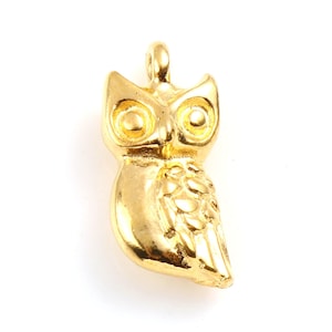 May include: A gold owl charm pendant with a detailed design. The owl has large, round eyes and a textured body.