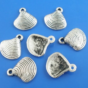 May include: Seven silver-toned metal clam shell charms with a textured surface. The charms have a loop at the top for attaching to jewelry or other crafts.