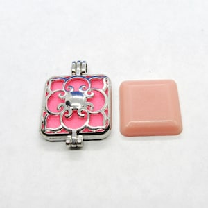May include: A silver locket with a pink floral design. The locket is open and the inside is empty.