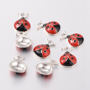 May include: Seven silver charms shaped like ladybugs with red and black enamel. The ladybugs have black spots and silver antennae.