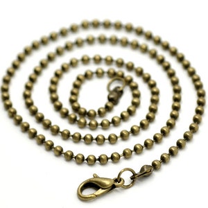 May include: A gold-toned ball chain necklace with a lobster clasp closure. The chain is made of small, round beads.