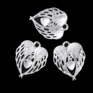 May include: Three silver metal charms in the shape of a heart with angel wings. Each charm has a smaller heart in the center.