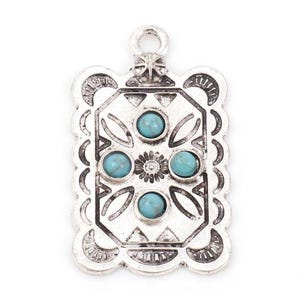 May include: A silver-toned rectangular pendant with a decorative design and five turquoise-colored stones. The pendant has a loop at the top for hanging and a detailed border. The central design includes a flower and geometric shapes.