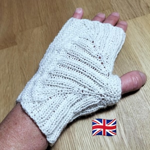Könnte beinhalten: Cremefarbener Strick-Fingerhandschuh mit einem strukturierten Muster. Der Handschuh ist aus einem weichen Material, möglicherweise Wolle oder Baumwolle. Das Design weist ein detailliertes Stichmuster und eine bequeme Passform auf.