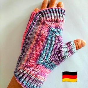 Könnte beinhalten: Ein fingerloser Handschuh mit einem mehrfarbigen Strickmuster in Rosa-, Lila- und Hellblautönen. Das Kleidungsstück verfügt über ein geripptes Bündchen am Handgelenk und eine separate Öffnung für den Daumen in glatt rechts gestrickt.