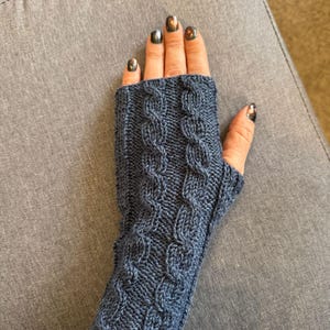 Könnte beinhalten: Ein Paar dunkelblaue Fingerlose Handschuhe mit einem Zopfmuster.