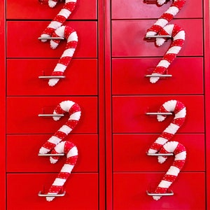 May include: Two red metal file cabinets with candy cane drawer pulls. Each cabinet has four drawers.