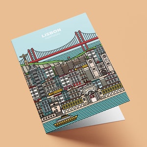 May include: A greeting card featuring a colorful illustration of Lisbon, Portugal. The design includes the 25 de Abril Bridge, buildings, and a boat on the water. The card has the words "LISBON PORTUGAL" at the top against a light blue sky.