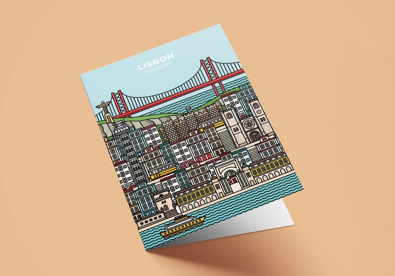 May include: A greeting card featuring a colorful illustration of Lisbon, Portugal. The design includes the 25 de Abril Bridge, buildings, and a boat on the water. The card has the words "LISBON PORTUGAL" at the top against a light blue sky.