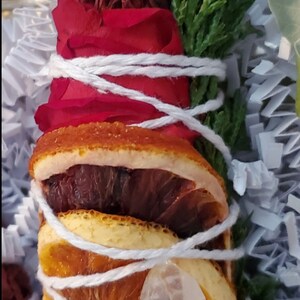 May include: A smudge stick wrapped in white twine with dried orange slices, a red rose, and a clear quartz crystal.