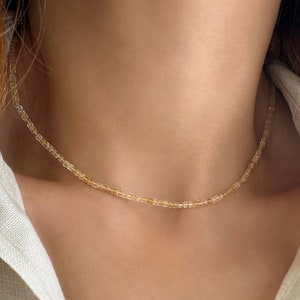 May include: A delicate gold and clear beaded choker necklace. The necklace is made of small, round beads that are strung together on a thin chain. The necklace is simple and elegant, and would make a great addition to any jewelry collection.