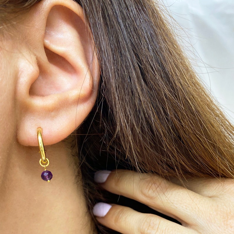 Chunky gold hoops with tiny raw stones.

Available with Amethyst or Peridot gems.

You can select the raw peridot earrings or the raw amethyst earrings.

Both small hoop earrings are a great option.
925 sterling silver and  a 24K gold finish