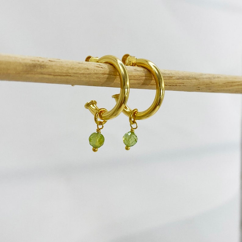 Chunky gold hoops with tiny raw stones.

Available with Amethyst or Peridot gems.

You can select the raw peridot earrings or the raw amethyst earrings.

Both small hoop earrings are a great option.
925 sterling silver and  a 24K gold finish