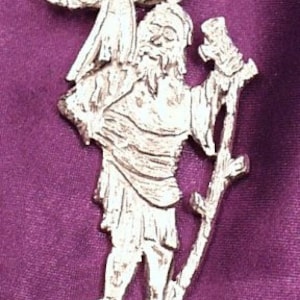 Op de afbeelding: Een zilverkleurige hanger die Sint Christoffel voorstelt die een kind op zijn schouders draagt. De hanger is gedetailleerd met een staf en een basis.