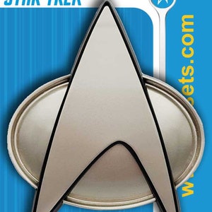 May include: A silver Star Trek insignia pin with a black outline. The pin is on a blue and white background with the words "STAR TREK" and "fansets.com".