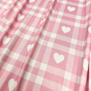 Puede incluir: Tela de cuadros rosa y blanca con un patrón de corazones blancos.