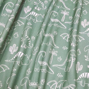Dubbelborstad polyeten, vita klotterdinosaurier på salviagrön bas, 180 gsm, 4-vägs stretch