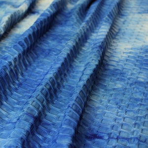 Op de afbeelding: Blauwe textuurstof met een subtiel ombre-effect, dat overgaat van een lichtere blauwe kleur naar een donkerdere blauwe kleur.
