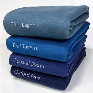 May include: Four different shades of blue fabric swatches stacked on top of each other. The swatches are labeled from top to bottom: Blue Lagoon, Teal Tavern, Coastal Storm, and Oxford Blue.