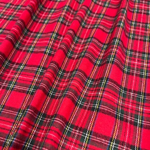 May include: Red and black plaid fabric with a subtle white and yellow thread woven into the pattern. The fabric is folded and has a soft, textured appearance.