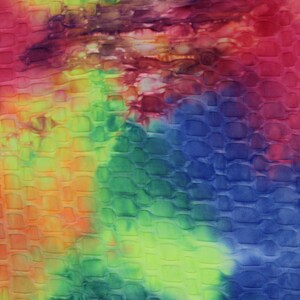 May include: A tie-dye fabric with a textured, embossed pattern. The fabric is a mix of blue, green, yellow, orange, and red colors.