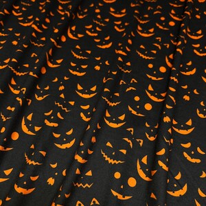 May include: Black fabric with a repeating pattern of orange jack-o'-lantern faces. The faces have various expressions, including smiling, grinning, and toothy grins. The Halloween-themed fabric is suitable for costumes, decorations, or crafts.