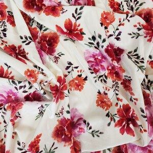 May include: White velvet fabric with a floral pattern in shades of pink, red, and orange. The flowers are stylised and have a watercolour effect.