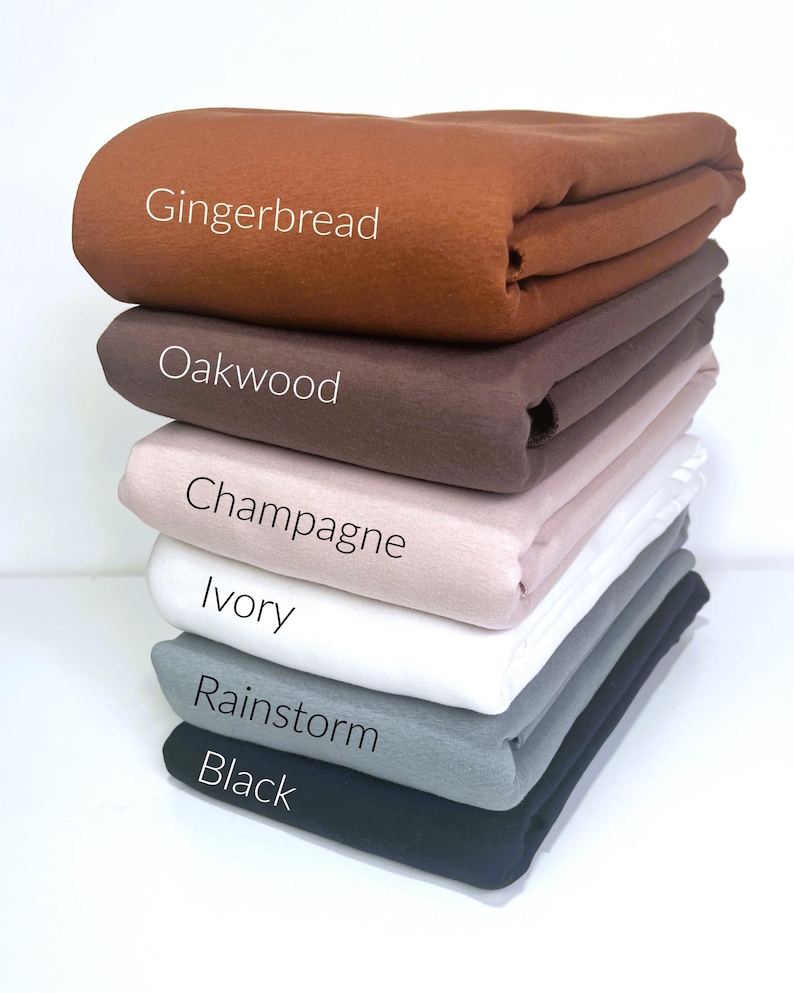 May include: A stack of six fabric swatches in various colors, including gingerbread, oakwood, champagne, ivory, rainstorm, and black.