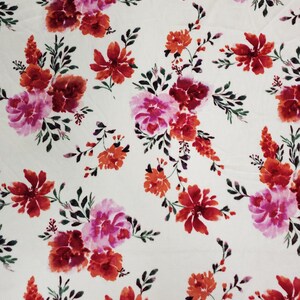 May include: White fabric with a repeating pattern of pink, red, and orange watercolour flowers. The flowers are stylised and have a painterly look.