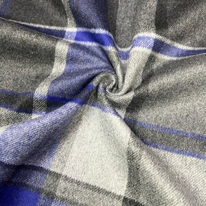 May include: Blue, gray, and white plaid fabric with a soft, textured feel. The fabric is folded and draped, showing the pattern and texture.