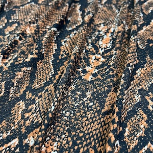 May include: Close-up of a brown and black fabric with a snake skin pattern.