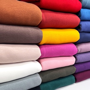 May include: A stack of colorful fabric swatches in various shades of brown, red, yellow, pink, purple, blue, and green. The fabric is soft and textured, and the colors are vibrant and rich.