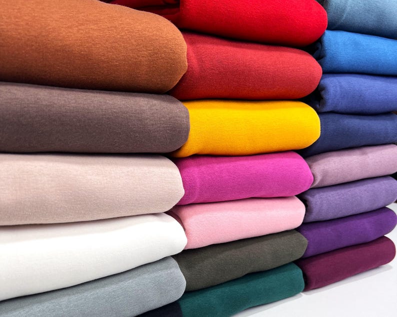 May include: A stack of colorful fabric swatches in various shades of brown, red, yellow, pink, purple, blue, and green. The fabric is soft and textured, and the colors are vibrant and rich.