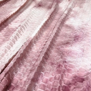 May include: A close-up of a pink and white textured fabric with a subtle tie-dye pattern. The fabric has a raised, waffle-like texture.
