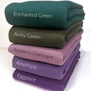 May include: Five different colors of fabric stacked on top of each other. The colors are Enchanted Green, Army Green, Raspberry Champagne, Amethyst, and Eggplant.