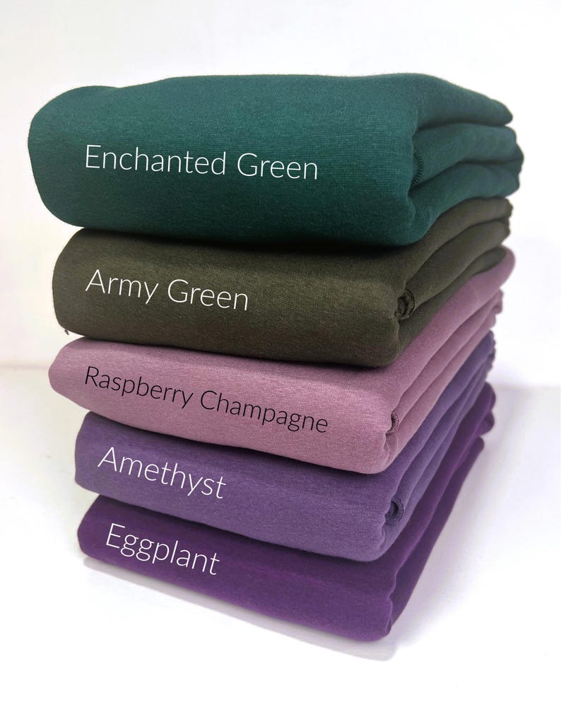 May include: Five different colors of fabric stacked on top of each other. The colors are Enchanted Green, Army Green, Raspberry Champagne, Amethyst, and Eggplant.